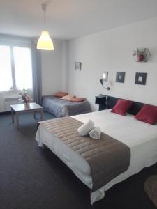 een slaapkamer met een groot bed en een kamer met 2 bedden bij Hotel la coursive in La Cotinière