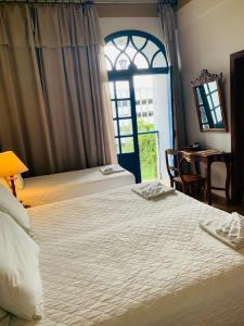 um quarto de hotel com duas camas e uma janela em Hotel Lenheiros em São João del Rei