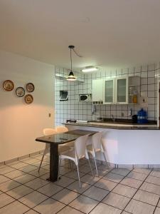 a kitchen with a table and chairs and a counter at Apartamento Pé na Areia e águas tranquilas no centro de Guarapari in Guarapari