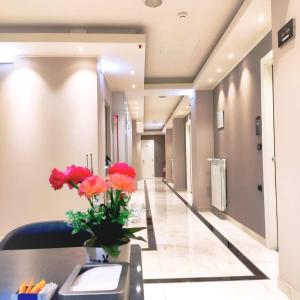 un couloir dans un hôpital avec des fleurs sur une table dans l'établissement Hotel Folen, à Milan