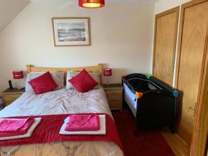 a bedroom with a bed with pink pillows and a suitcase at George's House - 1 Leacklee in Manish