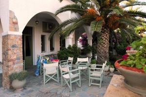 eine Terrasse mit Stühlen, einem Tisch und einer Palme in der Unterkunft Achilleion Hotel in Skyros