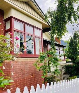 einen weißen Zaun vor einem Haus mit Fenster in der Unterkunft Warwick St Retreat! 3 Bedroom House With Parking in Hobart