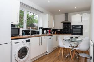 a kitchen with white cabinets and a table with chairs at Relaxation by Olauda SA - 3 Bed House with Free Parking in Bristol