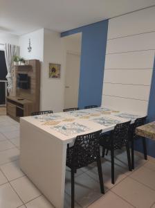a dining room table with chairs and a blue wall at Apartamento 500m Praia da Enseada Guarujá varanda e vaga de garagem in Guarujá