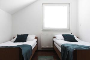 two beds in a room with a window at Vikend kuća Oskar in Kupres