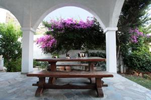 a wooden picnic table under an arch with purple flowers at Achilleion Hotel in Skiros
