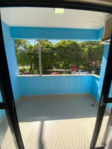 a room with a blue wall and a window at Apartamento 50m da praia no Jd atlântico in Ilhéus