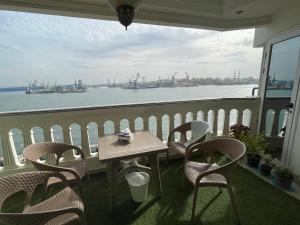 einen Tisch und Stühle auf einem Balkon mit Blick auf das Wasser in der Unterkunft شقة مطلة علي قناة السويس701 in Port Said