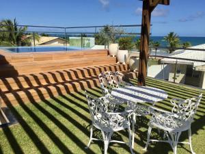 グアラジュバにあるCasa Estrela do Mar Guarajubaの海の景色を望む芝生の上にテーブルと椅子