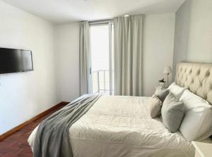 a bedroom with a large white bed with a window at Balcarce Deluxe in Cordoba