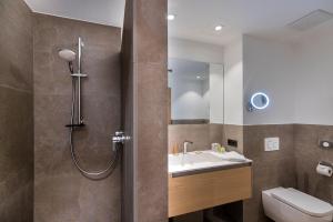 y baño con ducha, lavabo y aseo. en Defereggental Hotel & Resort en Sankt Veit in Defereggen