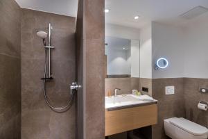 a bathroom with a shower and a sink and a toilet at Defereggental Hotel & Resort in Sankt Veit in Defereggen