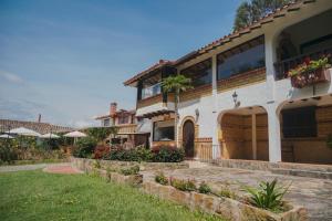 a large house with a porch and a yard at Bombon hotel spa in Villa de Leyva