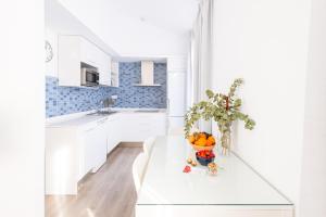 格拉纳达Apartamentos con encanto en el centro de Granada的白色的厨房,配有一张桌子和一碗橙子