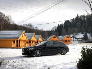 a black car parked in the snow in front of houses at Domki na Podgórzu in Duszniki Zdrój
