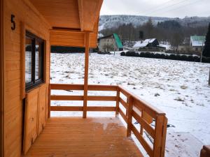 un porche de una cabaña con nieve en el suelo en Domki na Podgórzu en Duszniki Zdrój