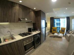 a kitchen with a stove top oven next to a living room at Luxury Apartment in DAMAC Towers in Amman