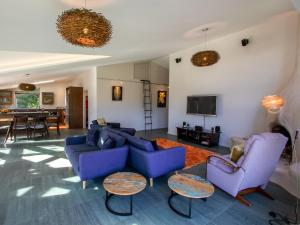 a living room with purple couches and a tv at Golden Paradise - Rangihaeata Holiday Home in Takaka