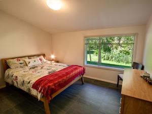 a bedroom with a bed and a window at Golden Paradise - Rangihaeata Holiday Home in Takaka