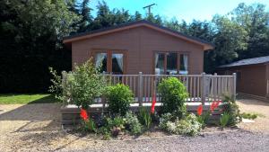 una pequeña casa con una valla y algunas plantas en King's Lynn Caravan & Camping Park en Kings Lynn