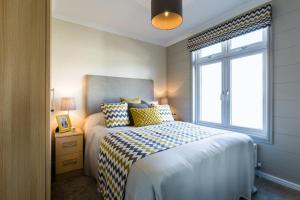 um quarto com uma cama com um cobertor xadrez e uma janela em King's Lynn Caravan & Camping Park em King's Lynn