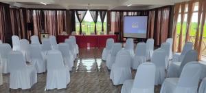 a conference room with white chairs and a screen at Tamteh Homestay in Ayer Hitam