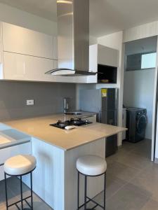 a kitchen with a counter and two stools in it at Apartasuite de lujo Distrito 90 in Barranquilla