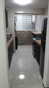 a kitchen with black cabinets and a white tile floor at Un pedacito de arena en Cancún in Cancún