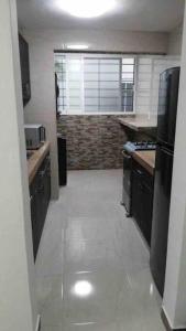 a kitchen with black cabinets and a white tile floor at Un pedacito de arena en Cancún in Cancún +2 photos
