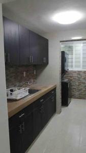 cocina con armarios negros y lavabo en una habitación en Un pedacito de arena en Cancún, en Cancún