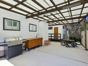 un patio con cocina, parrilla y mesa en Oceanside Cottage, en The Entrance