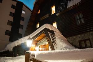 a house covered in snow in front of a building at Apartments Peggy in Jahorina