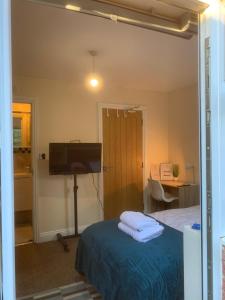 a bedroom with a bed and a desk and a piano at Cosy Room With Private Entrance & Ensuite in Reading