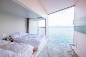 two beds in a room with a view of the water at 佐島 - Nowhere but Sajima - ペット可 in Yokosuka