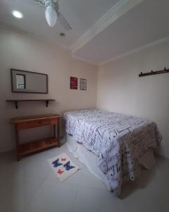 a white bedroom with a bed and a table at Casa com 2 quartos na Prainha em Arraial do Cabo, 20 METROS DA PRAIA in Arraial do Cabo