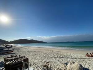 a beach with chairs and people on the sand at Casa com 2 quartos na Prainha em Arraial do Cabo, 20 METROS DA PRAIA in Arraial do Cabo