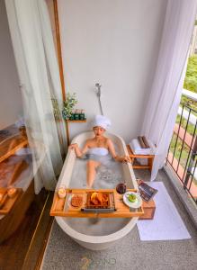 una mujer sentada en una bañera con una bandeja de comida en 22Land Hotel & Residence, en Hanói