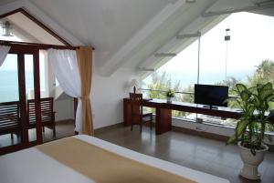 a bedroom with a bed and a desk and windows at Canary Beach Resort in Mui Ne