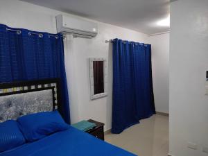a bedroom with a blue bed and blue curtains at Galerias Pelush 2 beedroom in San Pedro de Macorís