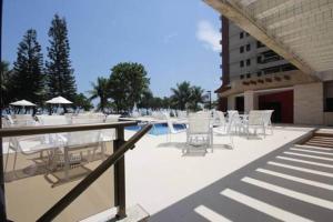 un patio con sedie, una piscina e un edificio di Flat Golden Coast a Rio de Janeiro