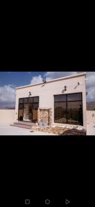 a white building with large windows in the desert at Estrahet Al Haitham in Al Qal‘ah