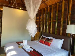 1 dormitorio con 1 cama con sábanas blancas y almohadas rojas en Say Love Baan Sapan บอกฮักบ้านสะปัน en Ban Huai Ti