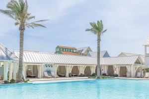a pool in front of a building with palm trees at Pelican's Perch at Palmilla Beach in Port Aransas