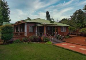 a brick house with a green roof and a yard at Highgarden Villa in Mahabaleshwar