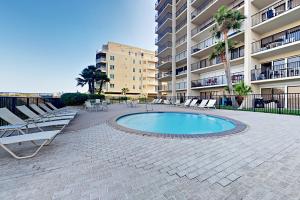 a patio with chairs and a pool in front of a building at Ocean Vista Condominiums #407 in South Padre Island