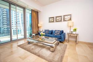 a living room with a blue couch and a table at Stylish and Sleek 1 Bed + Study near the JBR beach in Dubai