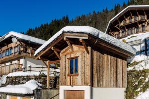Cabaña de madera con nieve en el techo en Petit Lumina en Morzine