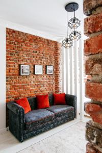a couch against a brick wall with red pillows at Centr VIP-kvartira by 7 in Minsk
