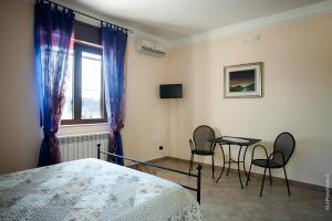 a bedroom with a bed and two chairs and a table at Villa Delle Palme in Trepuzzi